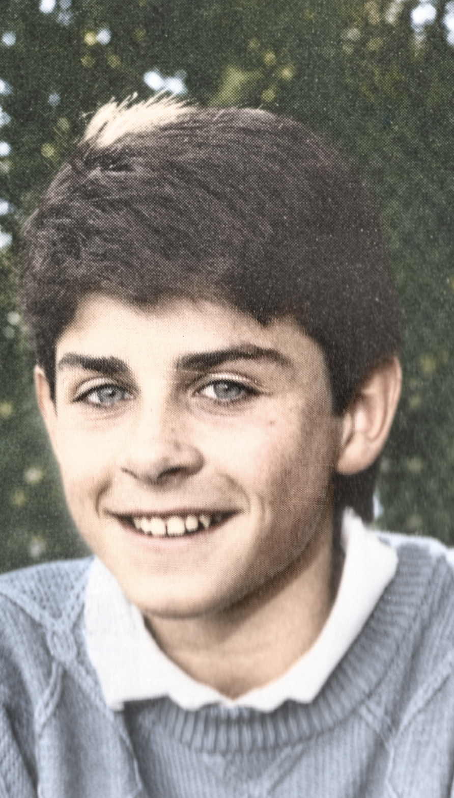 Chad at about thirteen, smiling outdoors in a collared shirt and sweater.
