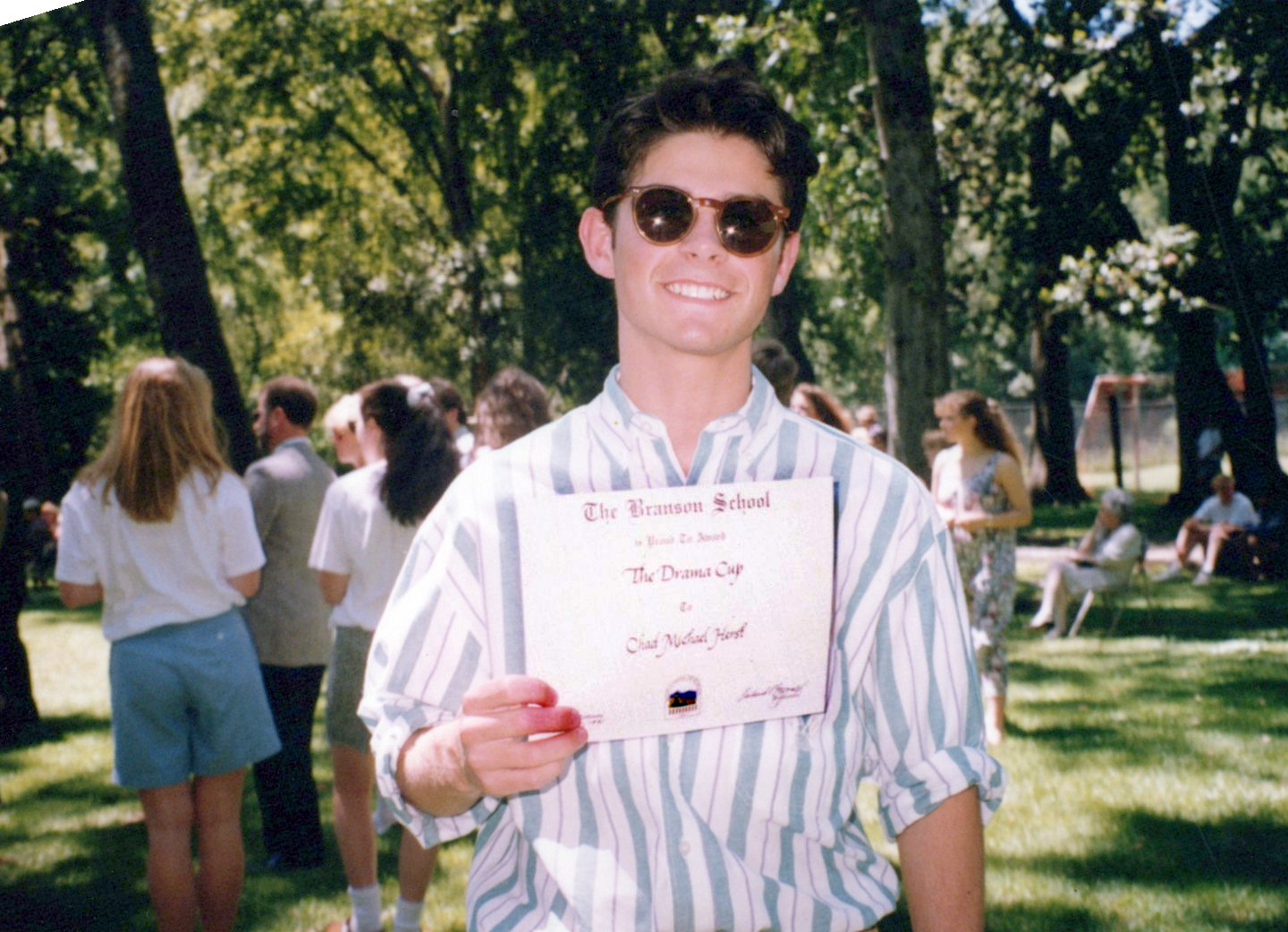 Chad outdoors at Branson School, holding a certificate for the Drama Cup.