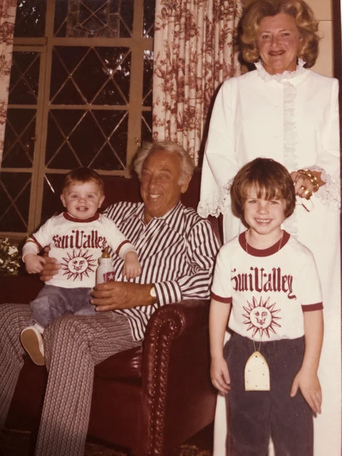 Two children with two older adults beside a leather armchair.