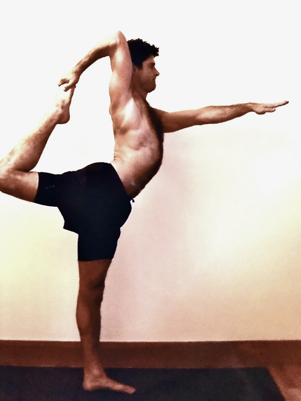 Chad balancing on one leg in a yoga posture, holding his raised foot behind him.